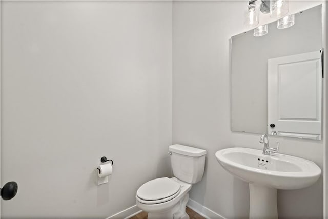 half bath featuring toilet and baseboards