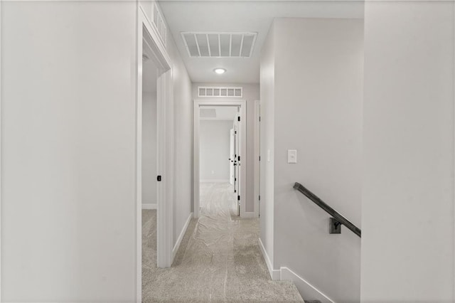 hallway with visible vents, an upstairs landing, carpet, and baseboards