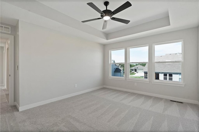 unfurnished room with visible vents, a raised ceiling, and light carpet