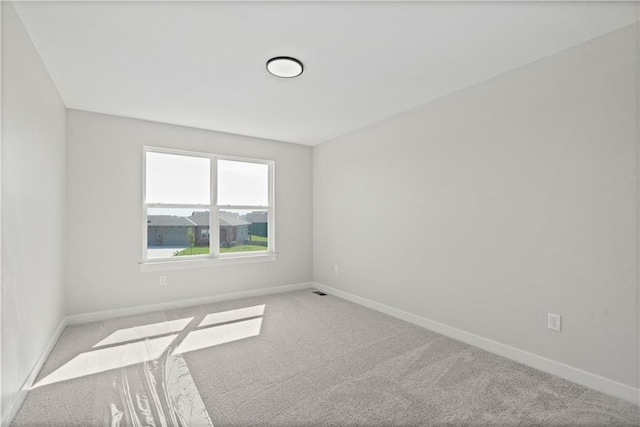 carpeted empty room featuring baseboards