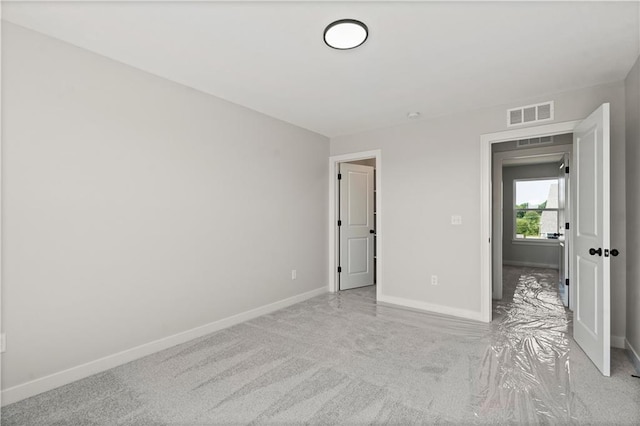 unfurnished bedroom with light carpet, visible vents, and baseboards