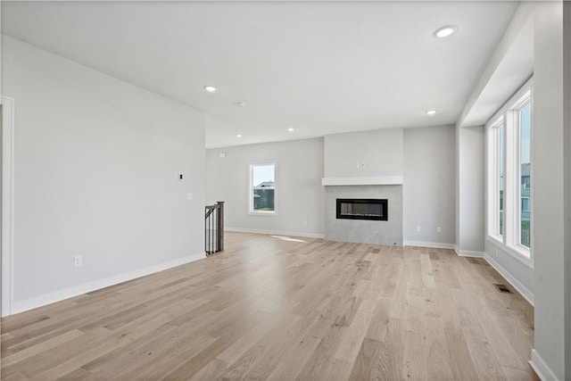 unfurnished living room featuring visible vents, a fireplace, light wood-type flooring, and baseboards