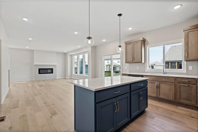 kitchen with light wood finished floors, a healthy amount of sunlight, tasteful backsplash, and a sink