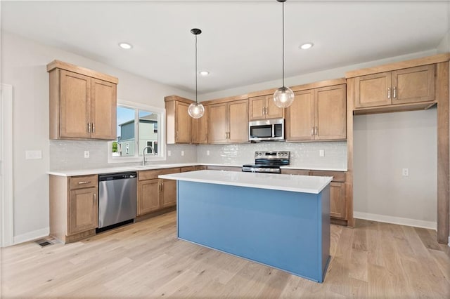 kitchen featuring a center island, decorative light fixtures, light wood-type flooring, light countertops, and stainless steel appliances