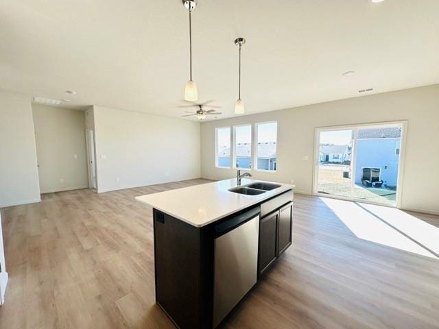 kitchen featuring open floor plan, light countertops, a sink, and light wood-style flooring