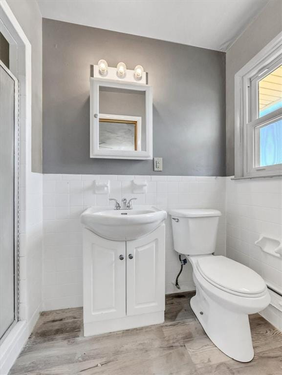 bathroom featuring vanity, toilet, an enclosed shower, and tile walls