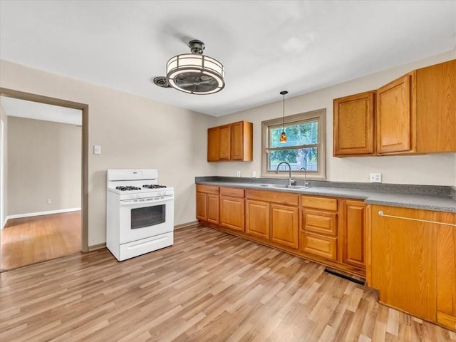 kitchen featuring white range with gas cooktop, light hardwood / wood-style flooring, sink, and hanging light fixtures