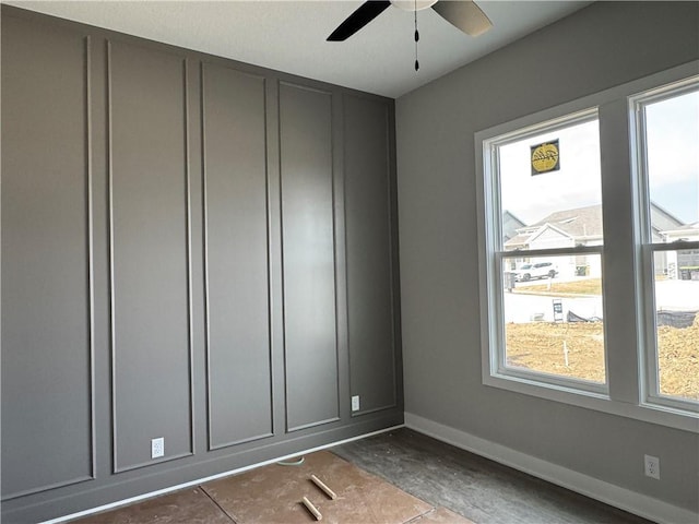 spare room with ceiling fan and baseboards