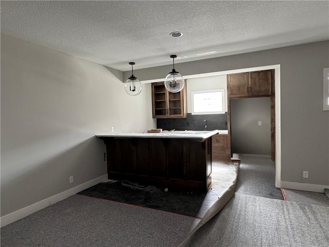 kitchen featuring a peninsula, baseboards, hanging light fixtures, light countertops, and carpet