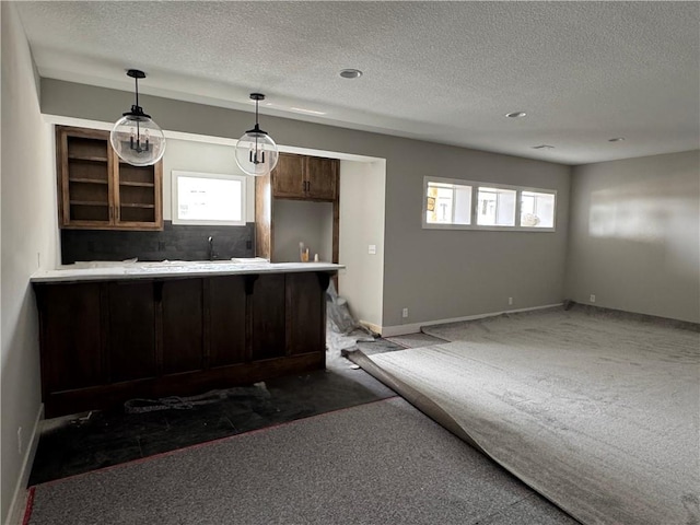 kitchen with baseboards, dark carpet, hanging light fixtures, a peninsula, and a kitchen breakfast bar