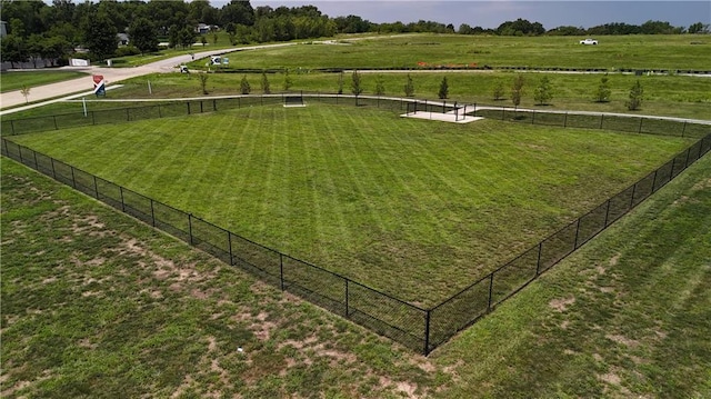 view of property's community featuring fence, a lawn, and a rural view