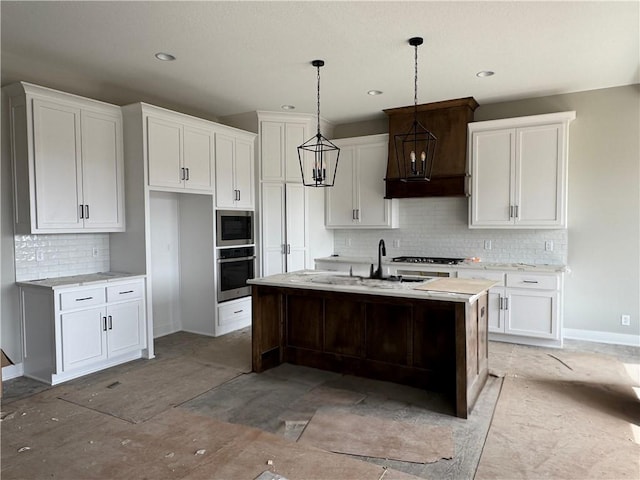 kitchen featuring a sink, light countertops, white cabinets, stainless steel appliances, and a kitchen island with sink