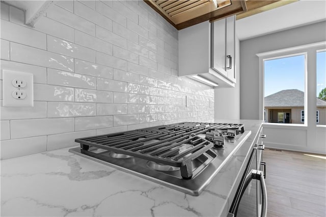 1511 SW Arbor Park Dr, Lees Summit, MO 64082 - kitchen featuring stainless steel gas cooktop, wall oven, decorative backsplash, light stone counters, and premium range hood
