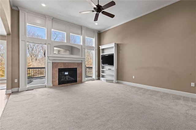 unfurnished living room featuring crown molding, carpet floors, ceiling fan, a fireplace, and a high ceiling