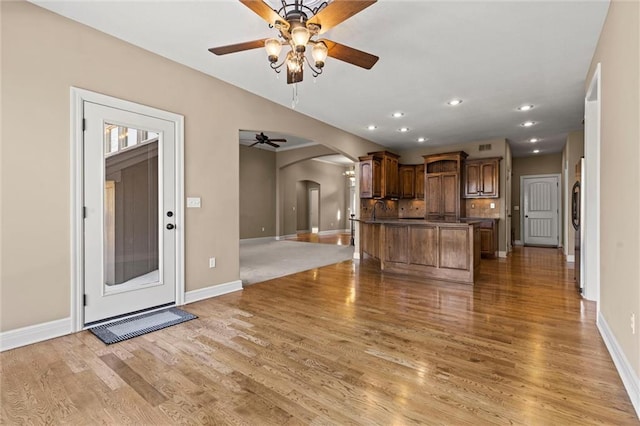 unfurnished living room featuring ceiling fan, sink, and light hardwood / wood-style flooring