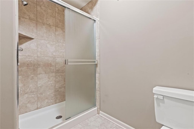 bathroom featuring tile patterned floors, toilet, and a shower with shower door