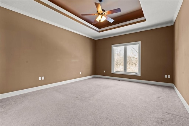 spare room featuring ceiling fan, ornamental molding, a tray ceiling, and light carpet