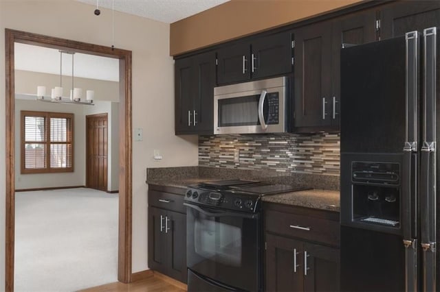 kitchen featuring decorative light fixtures, backsplash, dark stone counters, black appliances, and an inviting chandelier