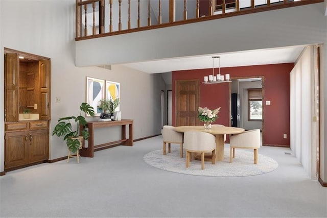 carpeted dining area featuring a chandelier and a high ceiling