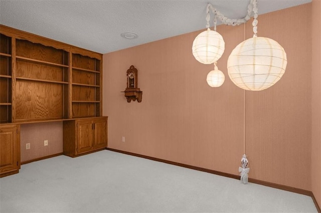 interior space featuring built in desk, light colored carpet, and a textured ceiling