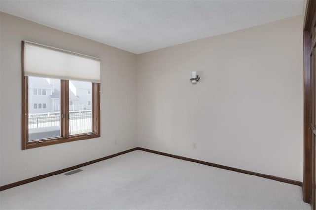 carpeted empty room featuring a textured ceiling