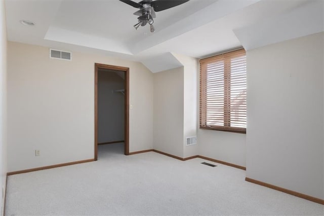 carpeted empty room featuring a raised ceiling and ceiling fan