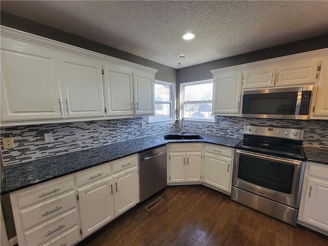 kitchen featuring sink, dark hardwood / wood-style floors, decorative backsplash, appliances with stainless steel finishes, and white cabinetry