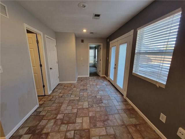 corridor with a healthy amount of sunlight and french doors