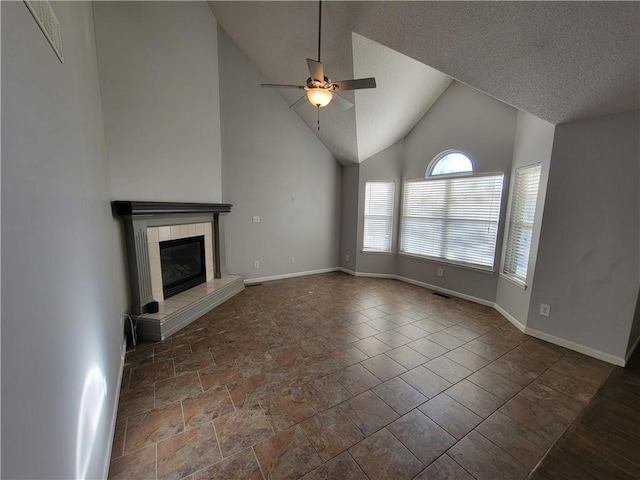 unfurnished living room featuring ceiling fan, a textured ceiling, high vaulted ceiling, and a tiled fireplace