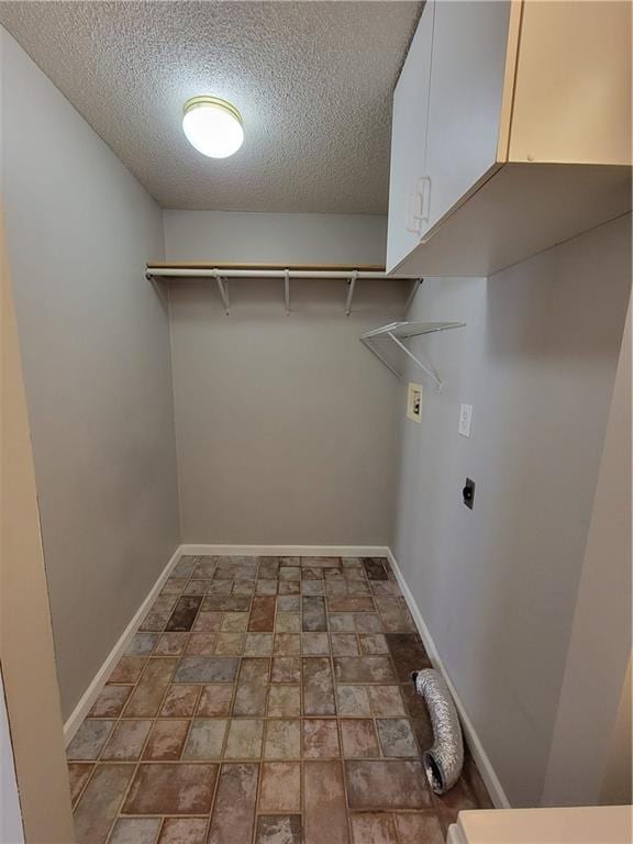 washroom featuring hookup for an electric dryer, cabinets, a textured ceiling, and hookup for a washing machine