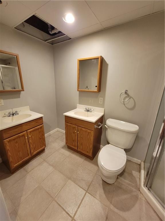 bathroom with tile patterned floors, vanity, a shower with shower door, and toilet