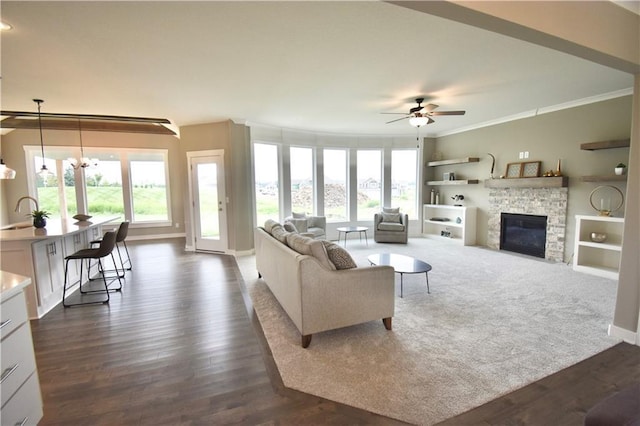 living room featuring ceiling fan with notable chandelier, a fireplace, a wealth of natural light, and dark hardwood / wood-style floors