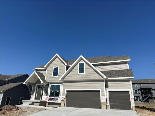 view of front of property with an attached garage, a shingled roof, and driveway