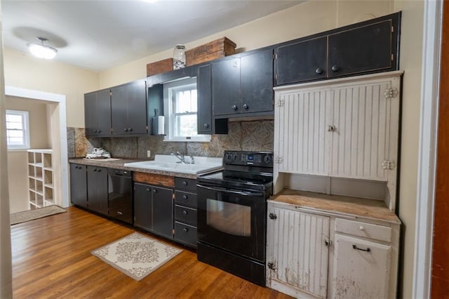 kitchen featuring light wood-type flooring, black appliances, tasteful backsplash, and sink