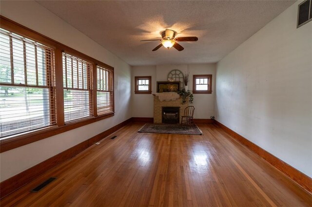 unfurnished living room featuring a fireplace, hardwood / wood-style flooring, plenty of natural light, and ceiling fan