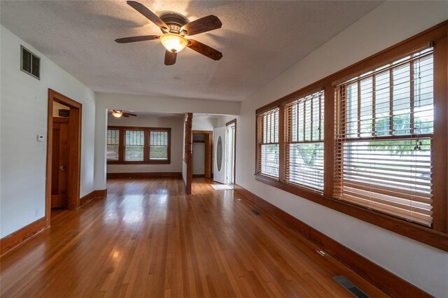 unfurnished living room with a textured ceiling, hardwood / wood-style floors, and ceiling fan