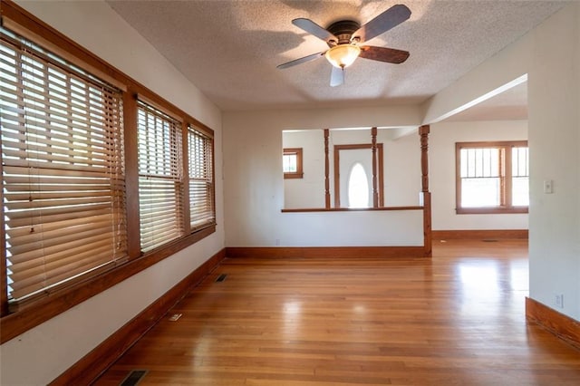 unfurnished room featuring hardwood / wood-style floors, ceiling fan, plenty of natural light, and a textured ceiling