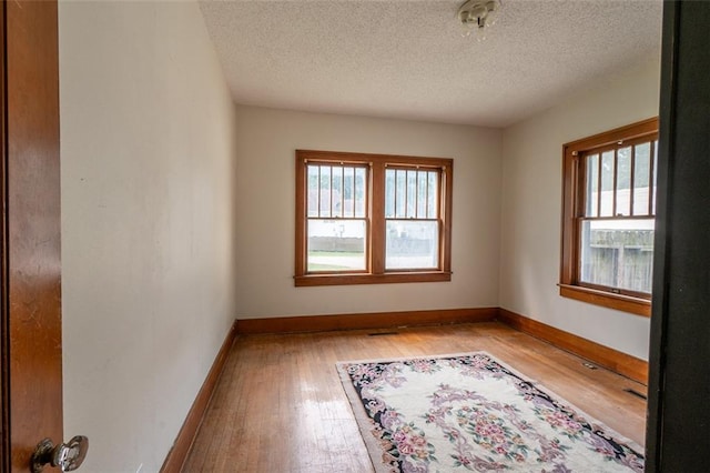 empty room with light wood-type flooring and a textured ceiling