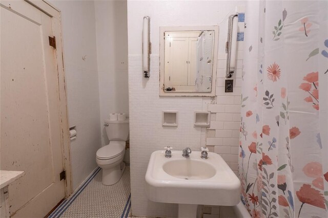 bathroom with tile patterned flooring, toilet, curtained shower, and sink