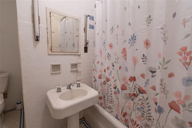 bathroom featuring tile walls and toilet