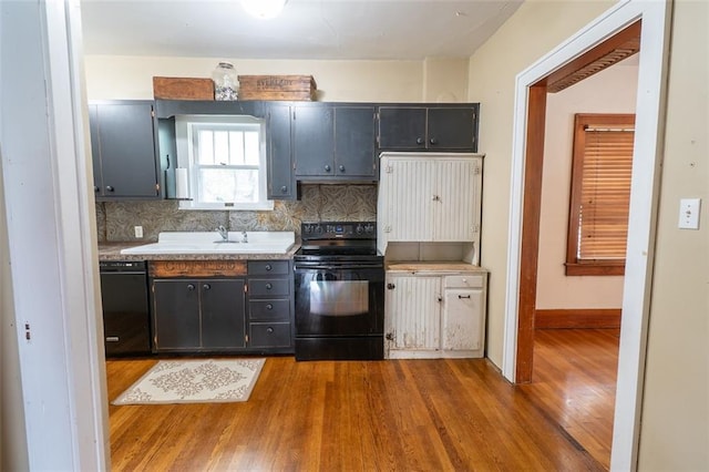 kitchen featuring black appliances, sink, decorative backsplash, and hardwood / wood-style flooring