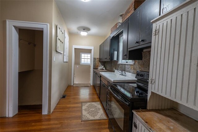 kitchen featuring hardwood / wood-style flooring, backsplash, sink, and electric range