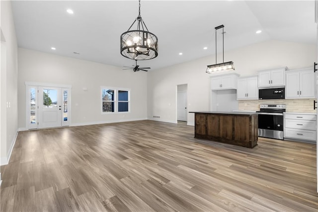 kitchen featuring backsplash, a kitchen island, stainless steel electric range oven, white cabinets, and ceiling fan with notable chandelier