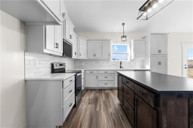 kitchen with white cabinets, stainless steel electric range, decorative light fixtures, and dark hardwood / wood-style floors