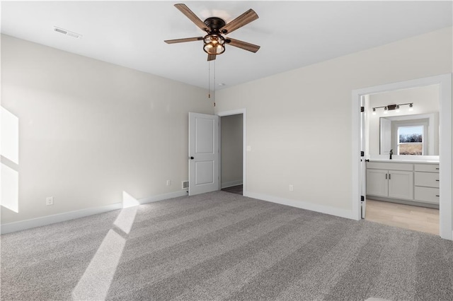 unfurnished bedroom featuring ensuite bathroom, light colored carpet, and ceiling fan