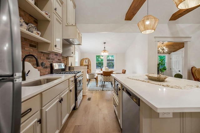 kitchen featuring pendant lighting, appliances with stainless steel finishes, a center island, and sink