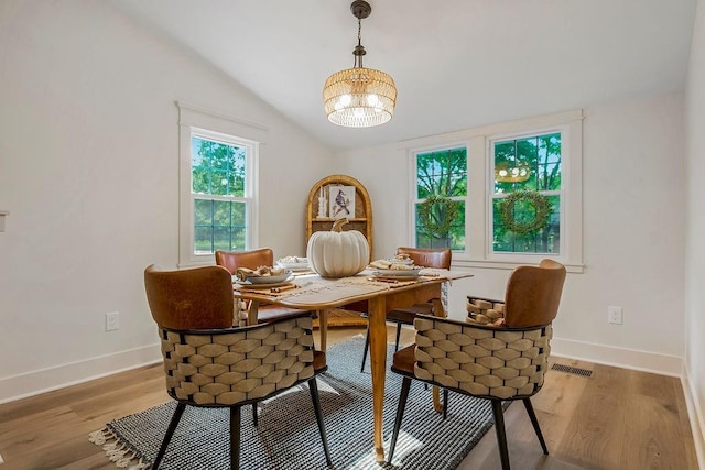 dining area featuring lofted ceiling, light hardwood / wood-style floors, and an inviting chandelier