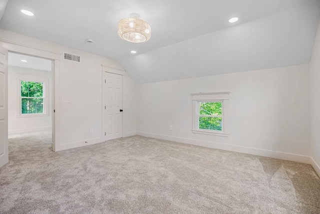 additional living space featuring vaulted ceiling and light colored carpet