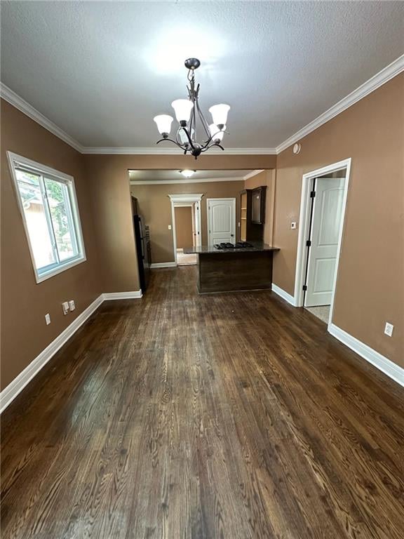 unfurnished living room with a textured ceiling, crown molding, dark hardwood / wood-style floors, and a chandelier