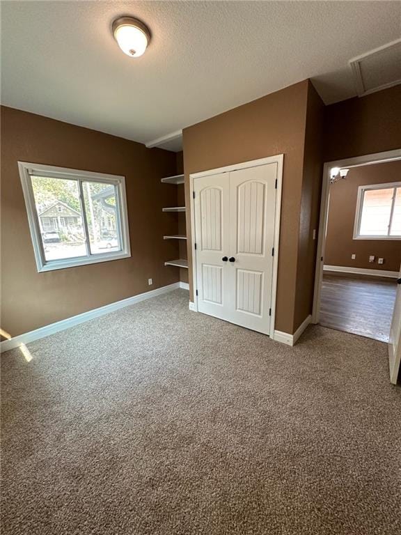 unfurnished bedroom with a textured ceiling, carpet flooring, and multiple windows